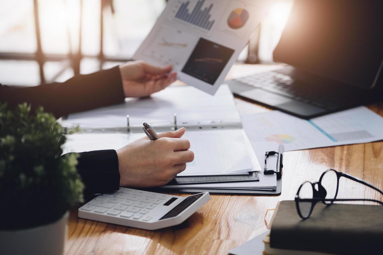 Sales Profitability Planning Idea, Businessman is holding a pen to analyze the profitability statistics from the graph document in hand to plan the profits in growth from the past year. photo