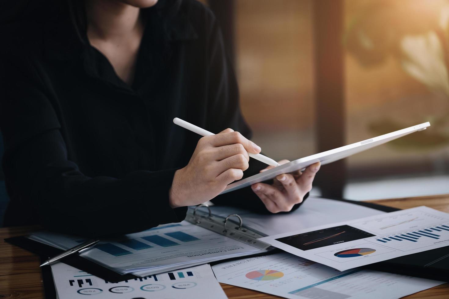 Electronic work concept, female employee is using tablet and ducument to analyze company profits to improve revenue over last year. photo