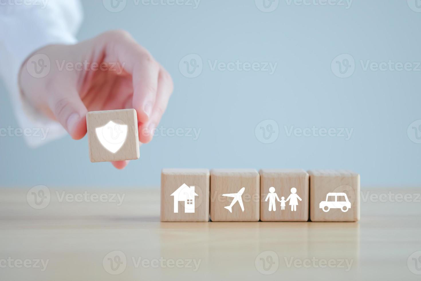 Insurance concept. Protection against a possible eventuality. Hand holding security icon and House, Car, Family and travel icon on wooden block for assurance life concept. photo