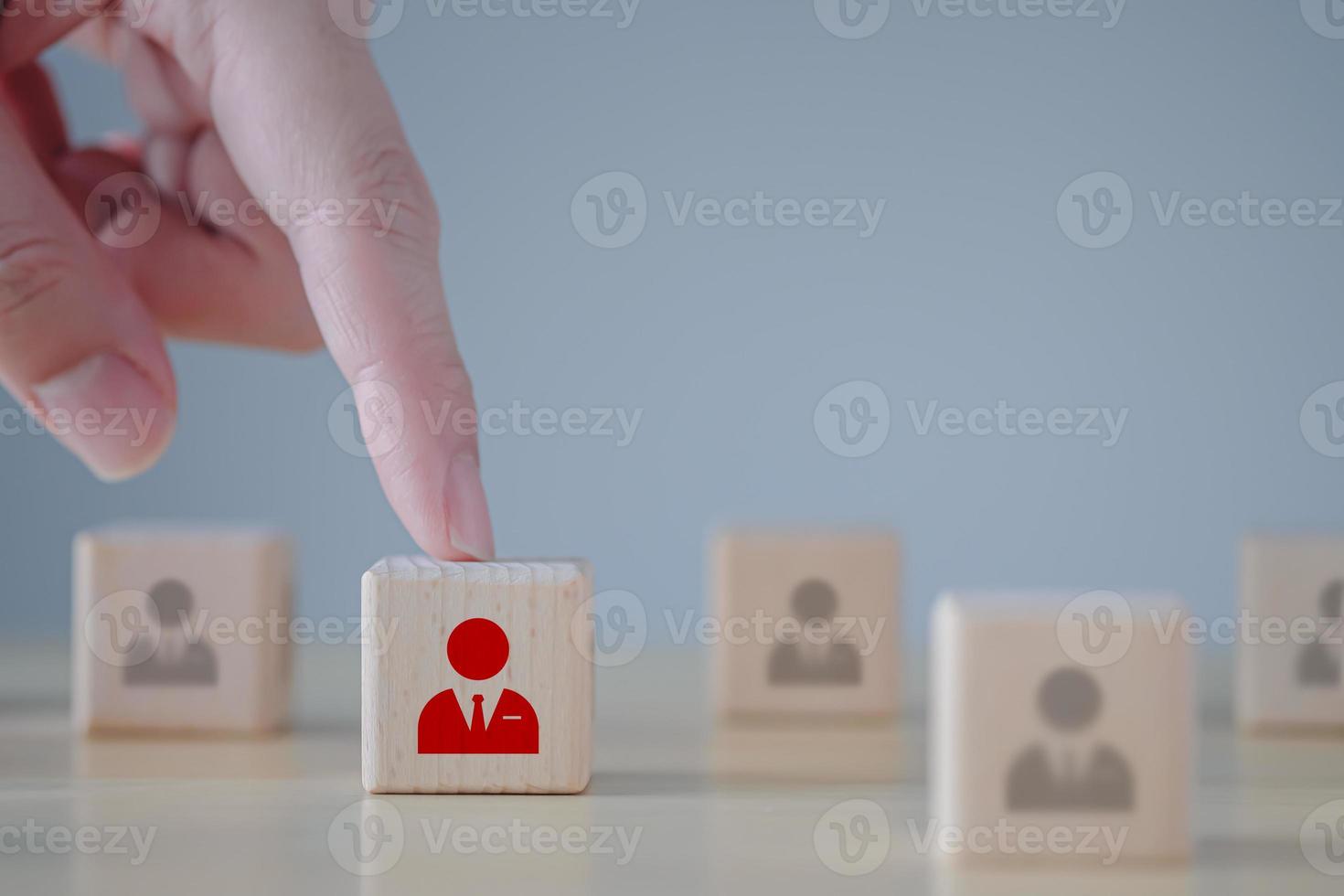 Business hiring and recruitment selection. Career opportunity. Human Resource Management. Hand choosing red businessman icon on wooden block. Choice of employee leader from the crowd. photo