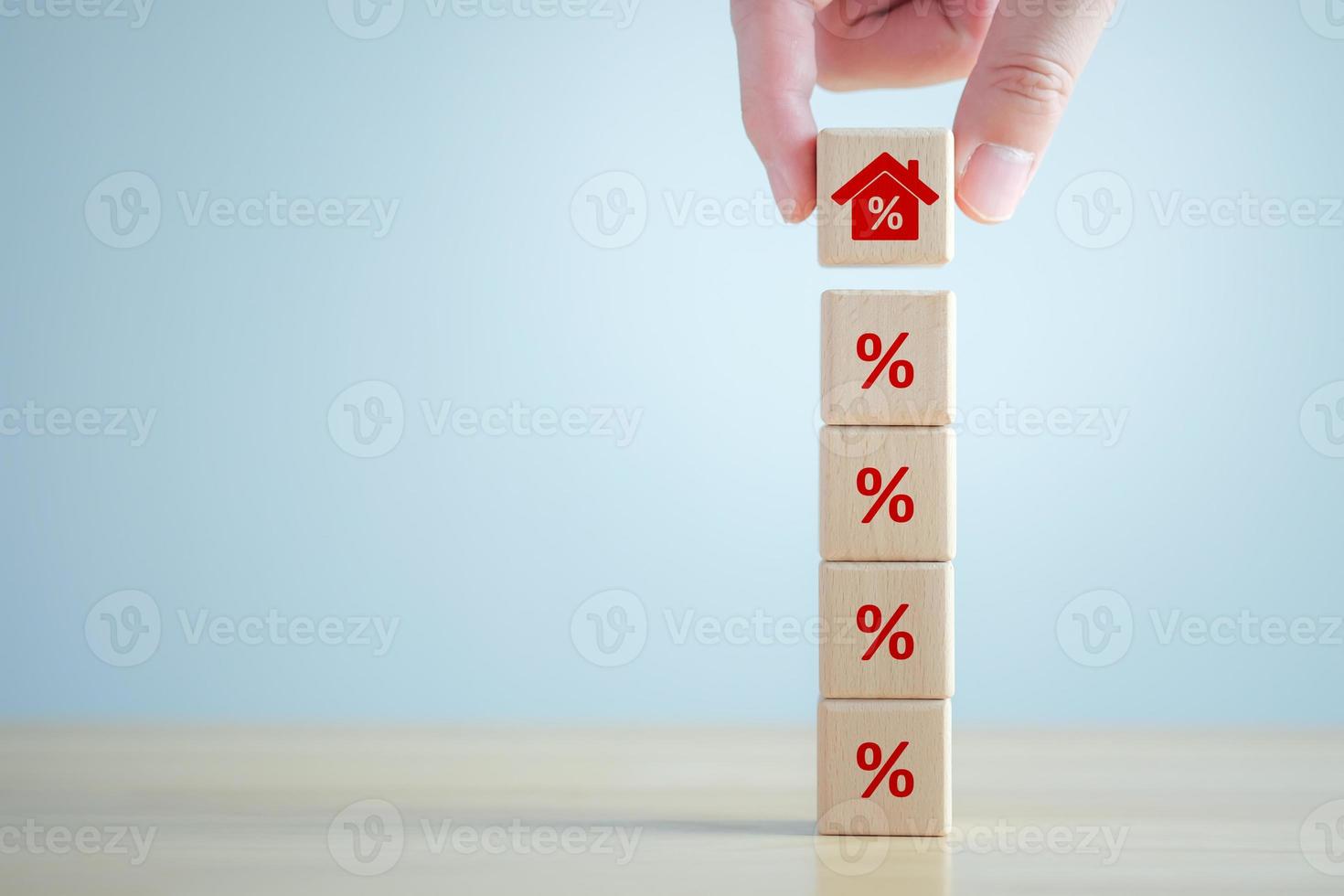 House and property investment and asset management concept. Interest rates, loan mortgage, house tax. Hand holding house icon on wooden block from stack of percentage icon. photo