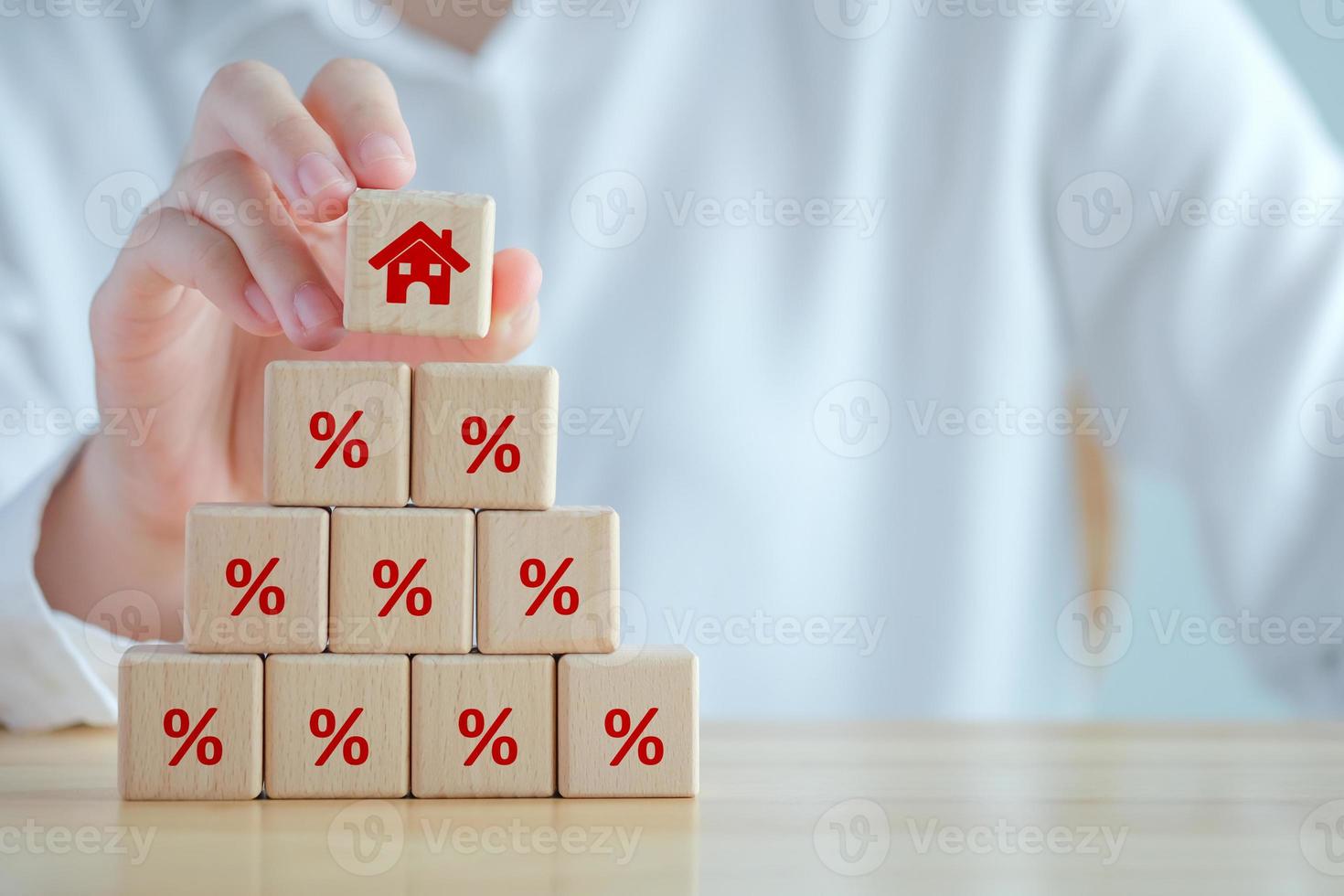 House and property investment and asset management concept. Interest rates, loan mortgage, house tax. Hand holding house icon on wooden block from stack of percentage icon. photo