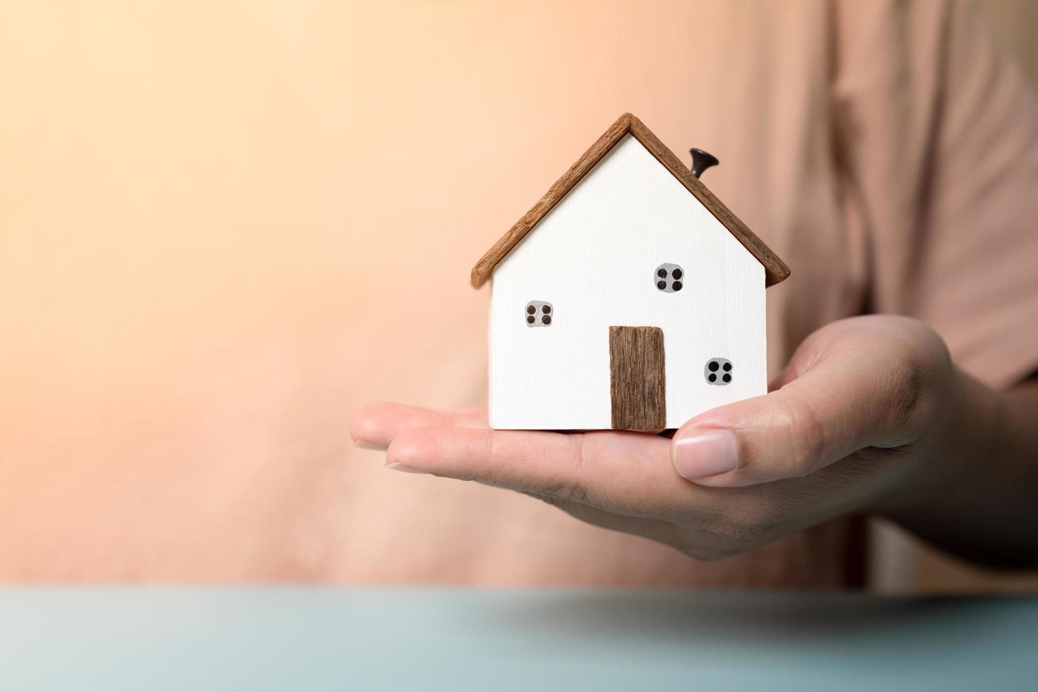 Hands holding small wooden house concept of protection or saving for new residential project. photo