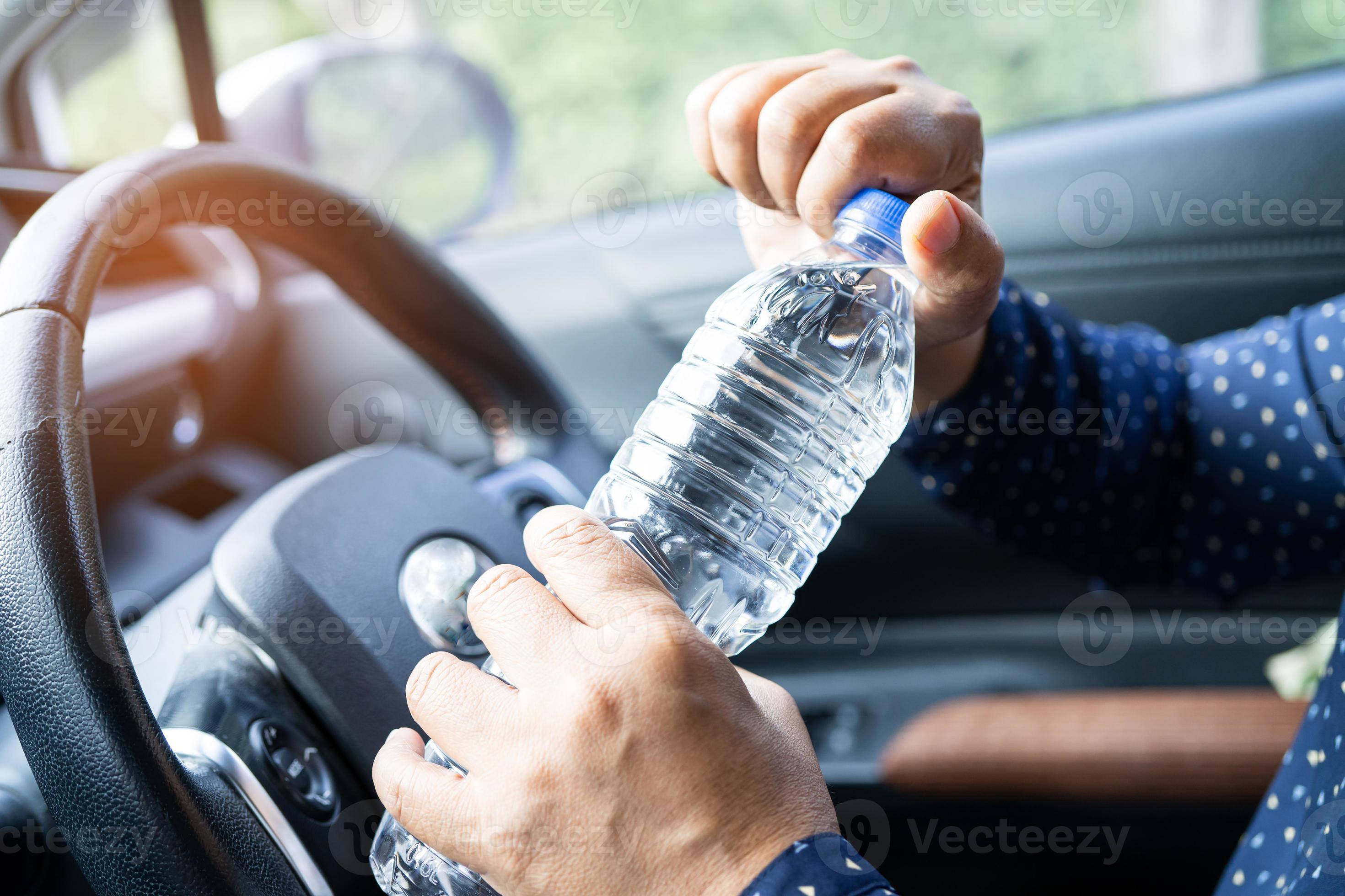 Asian woman driver holding bottle for drink water while driving a car
