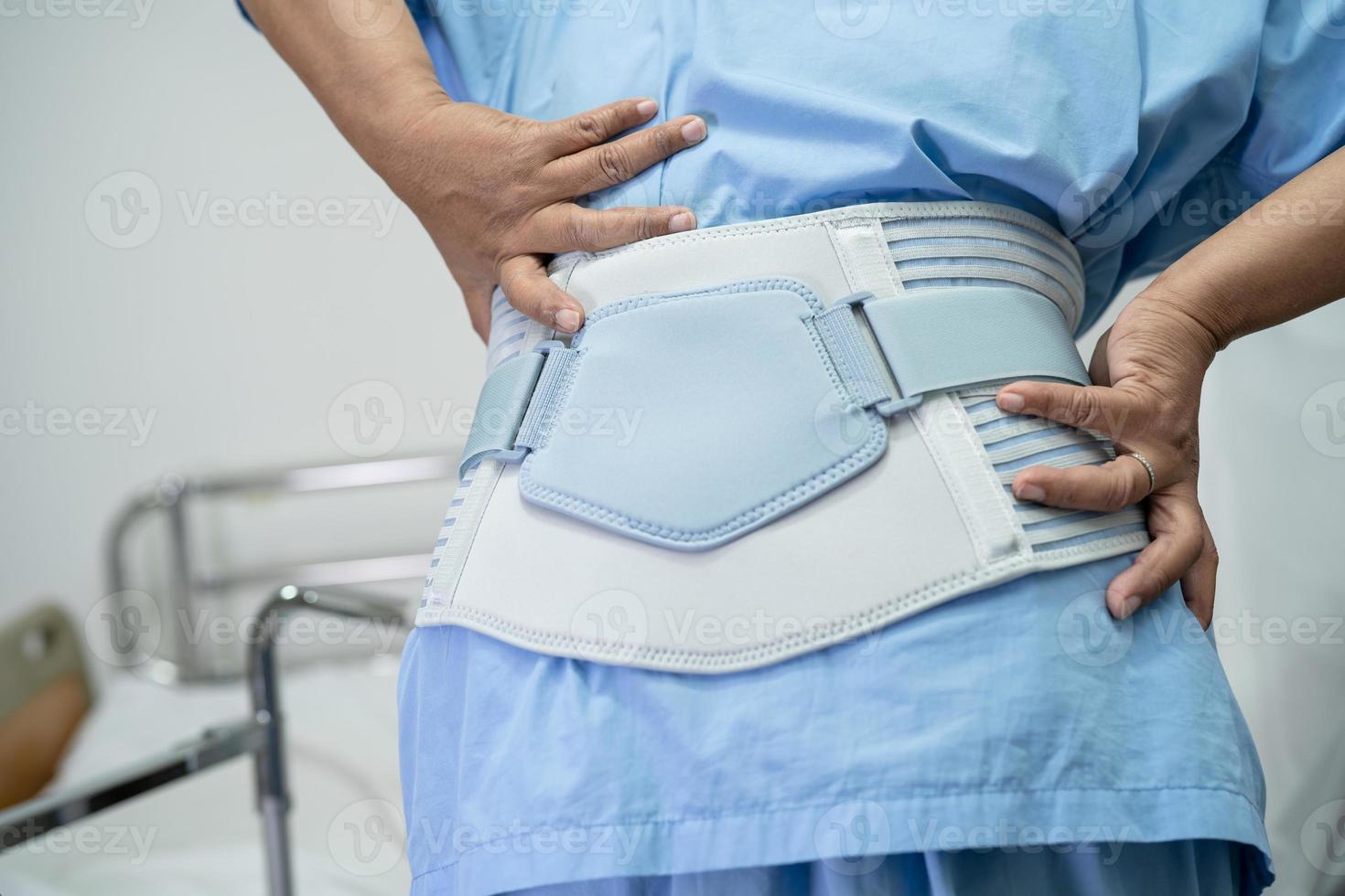 Asian lady patient wearing back pain support belt for orthopedic lumbar with walker. photo