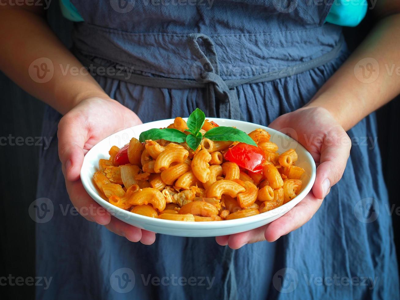 Woman hold a dish of macaroni with tomato sauce in hand photo