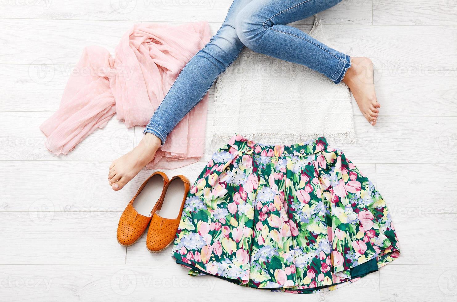 Stylish outfit with accessories and female legs on white wooden background. Top view and copy space photo