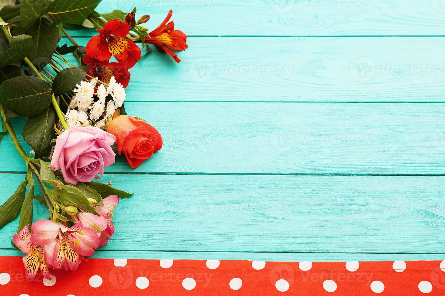 Frame of flowers and tablecloth in polka dots on blue wooden cooking workplace. Top view and selective focus. Copy space photo