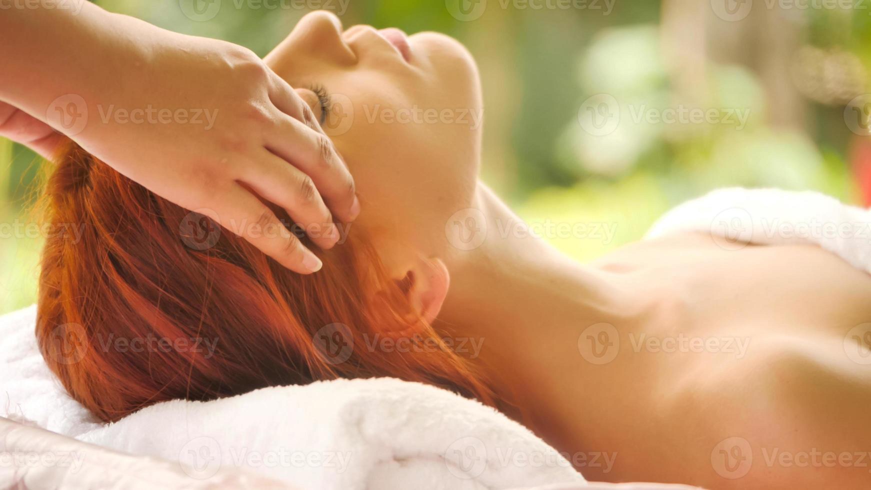hermosa mujer caucásica recibiendo masaje en la cabeza en el spa. foto