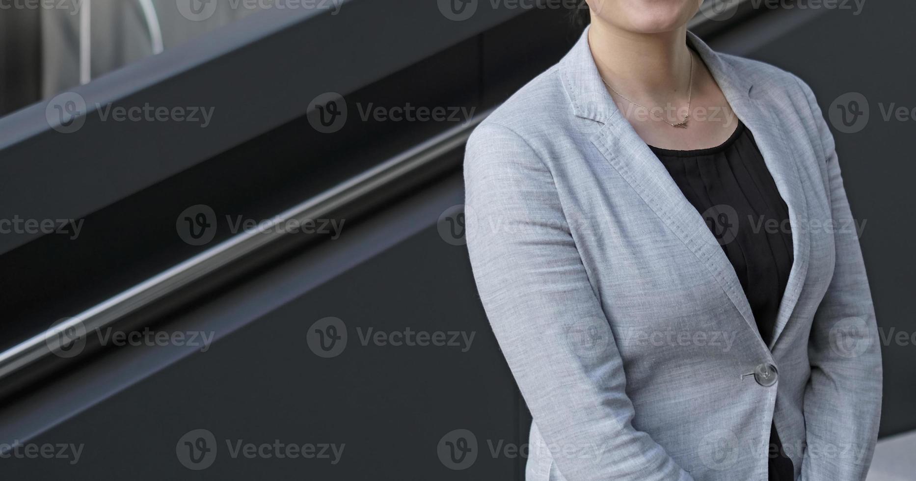 Anonymous female professional in a black shirt and grey suit jacket in an urban environment photo