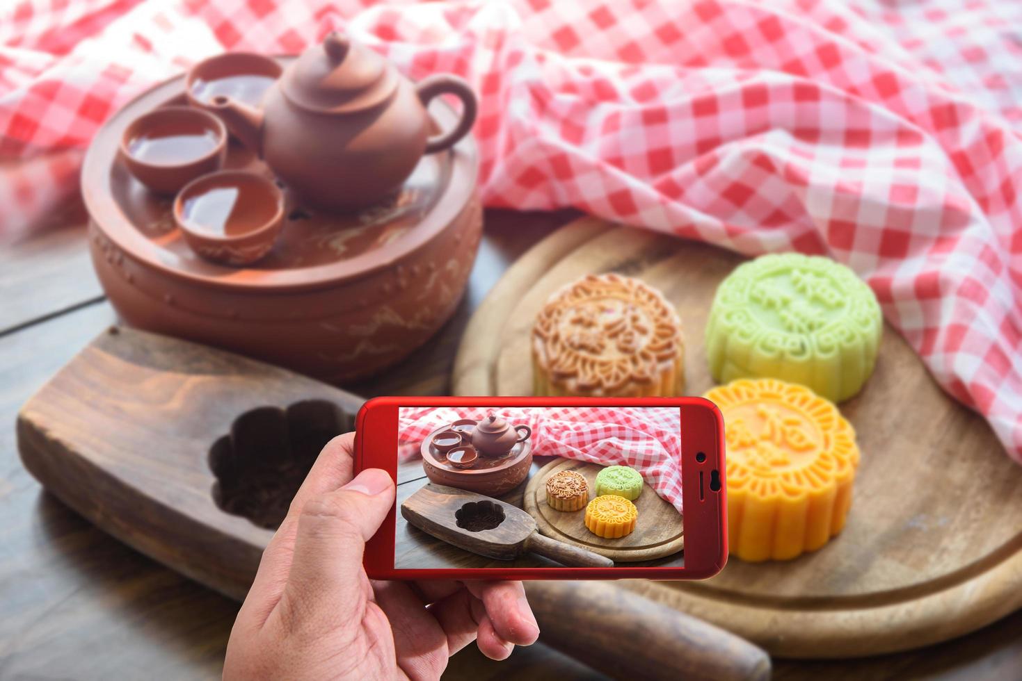 tomando fotos de pasteles de luna tradicionales en la mesa con una taza de té.