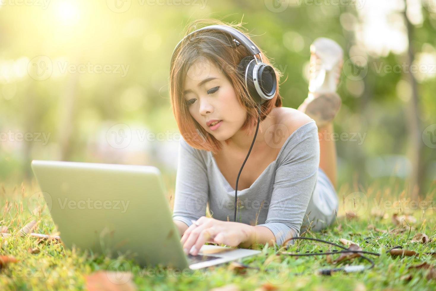 Young girl listening to music with headphone in city park photo