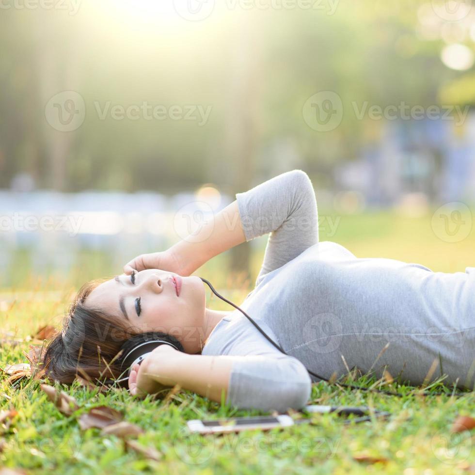 Young girl listening to music with headphone in city park photo
