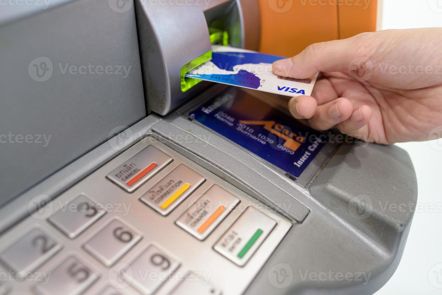 la mano de la mujer pone la tarjeta de crédito en el cajero automático foto