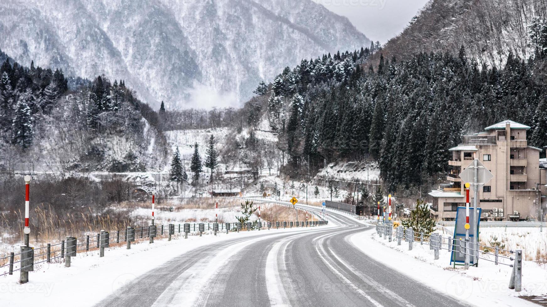 Empty snow covered road in winter landscape photo