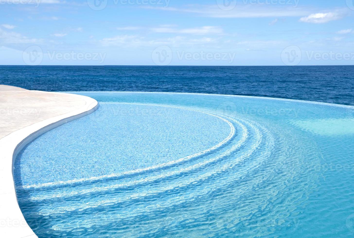 The wind makes water ripple. Sea water pool with stairs for relaxing. Blue clear water surface in swimming pool. Summer Vacation and rest concept. Pattern of bottom made of mosaic ceramic blue tiles. photo