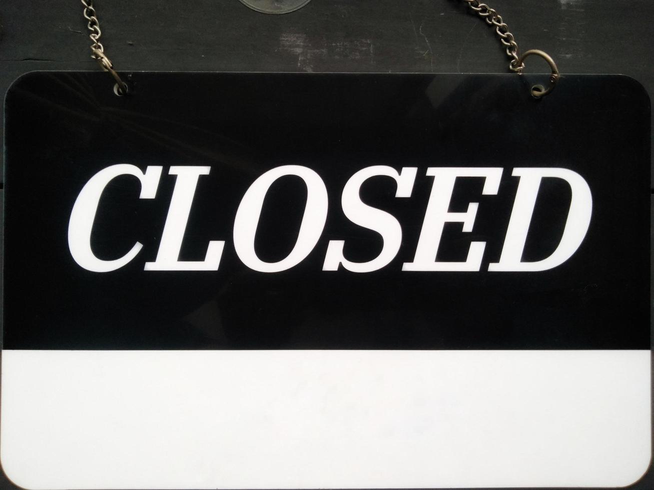 Closed signboard black and white color with a symbol that means Shop is closed. Hanging on a wooden wall. photo