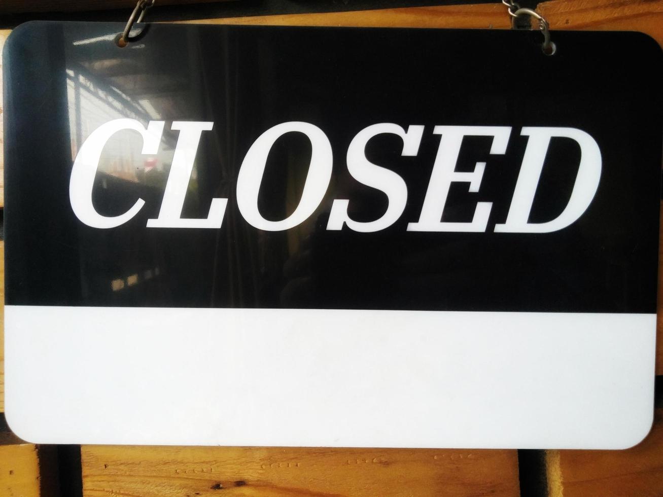 Closed signboard black and white color with a symbol that means Shop is closed. Hanging on a wooden wall. photo