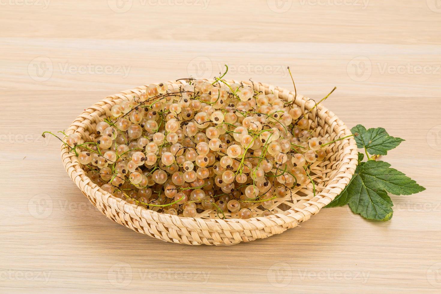 White currant in a basket on wooden background photo