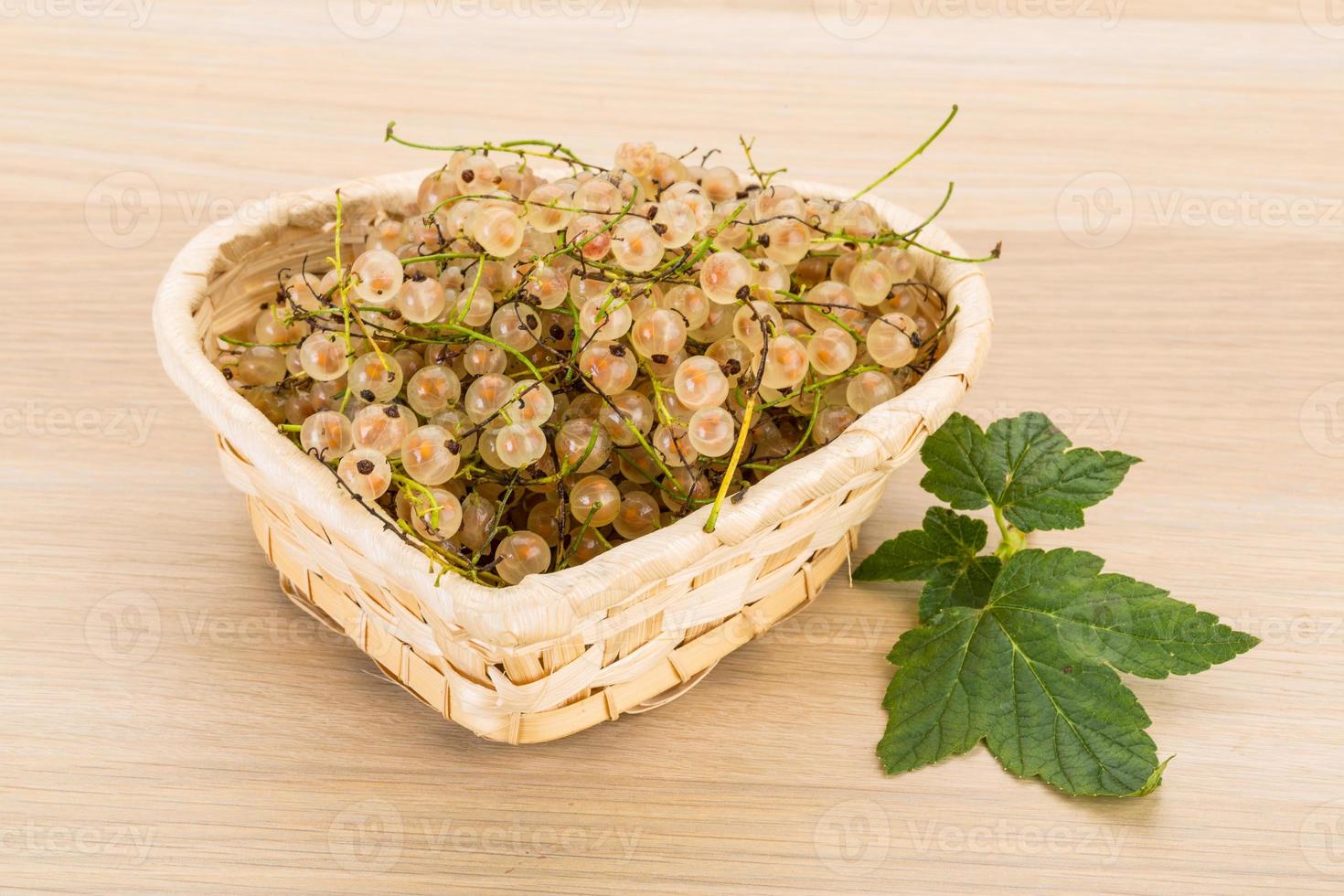 White currant in a basket on wooden background photo