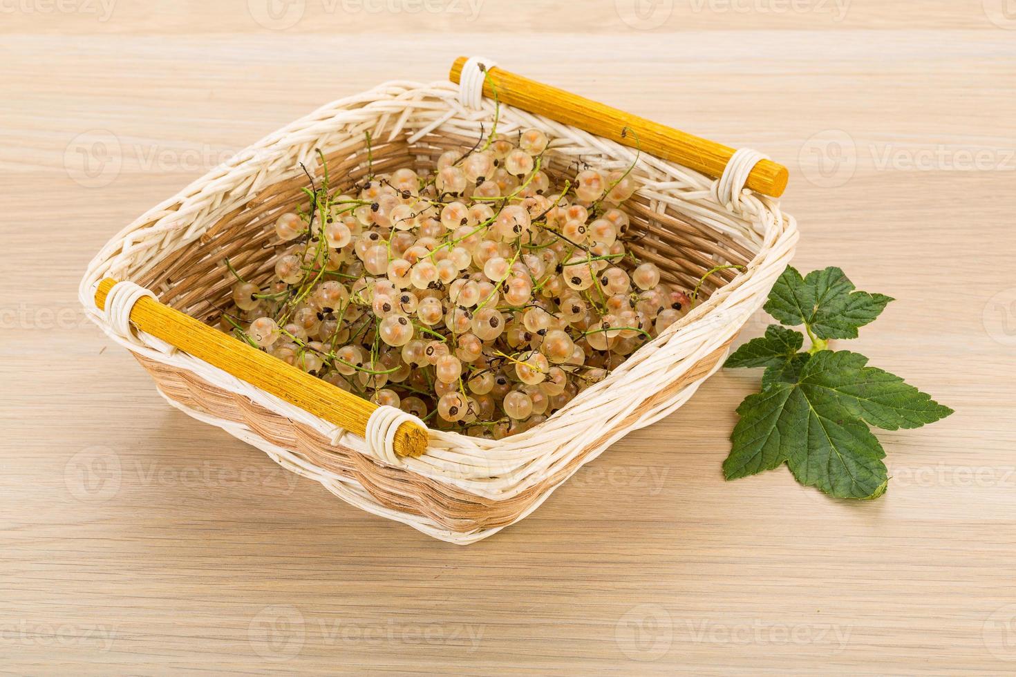 White currant in a basket on wooden background photo