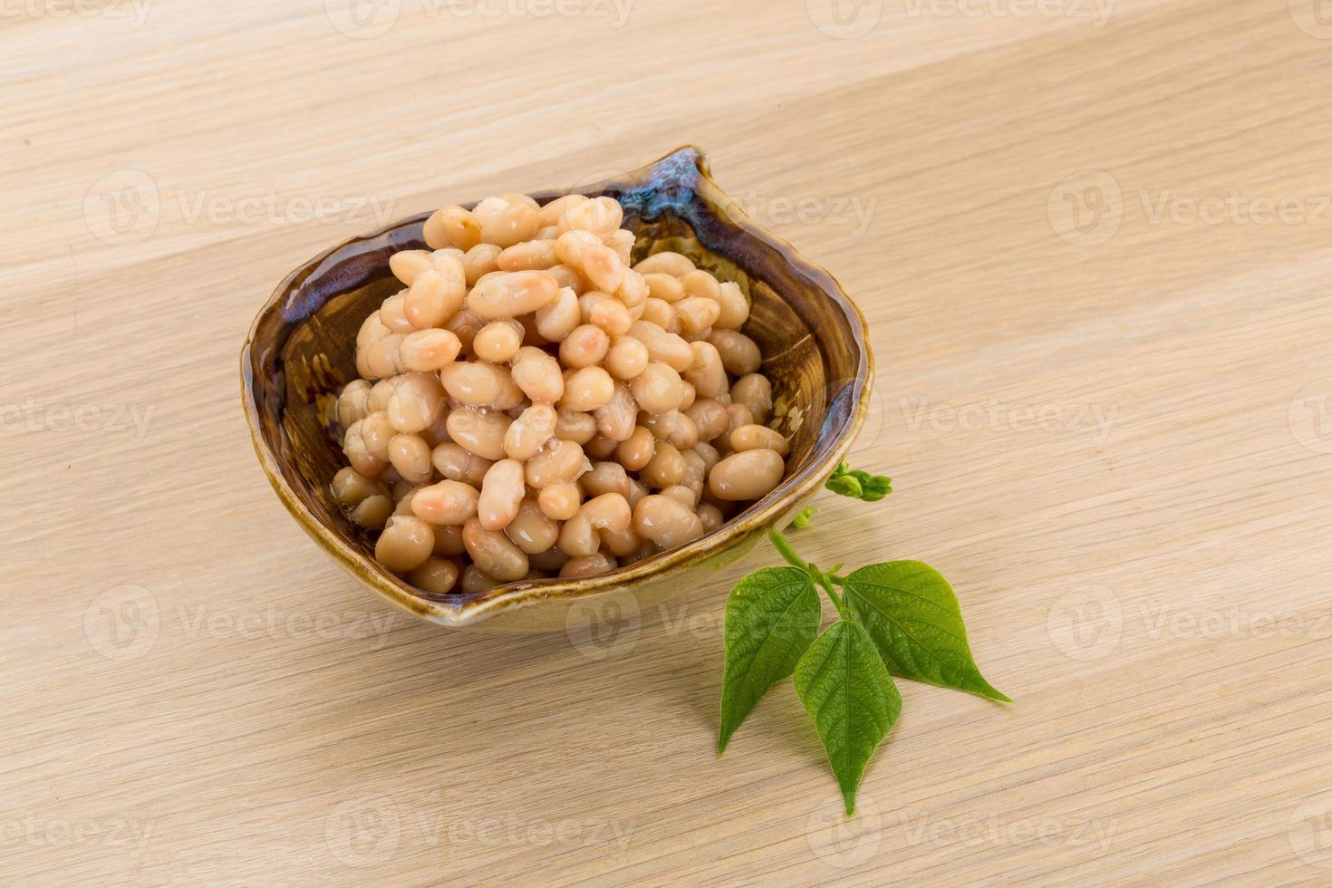 frijoles blancos en un recipiente sobre fondo de madera foto