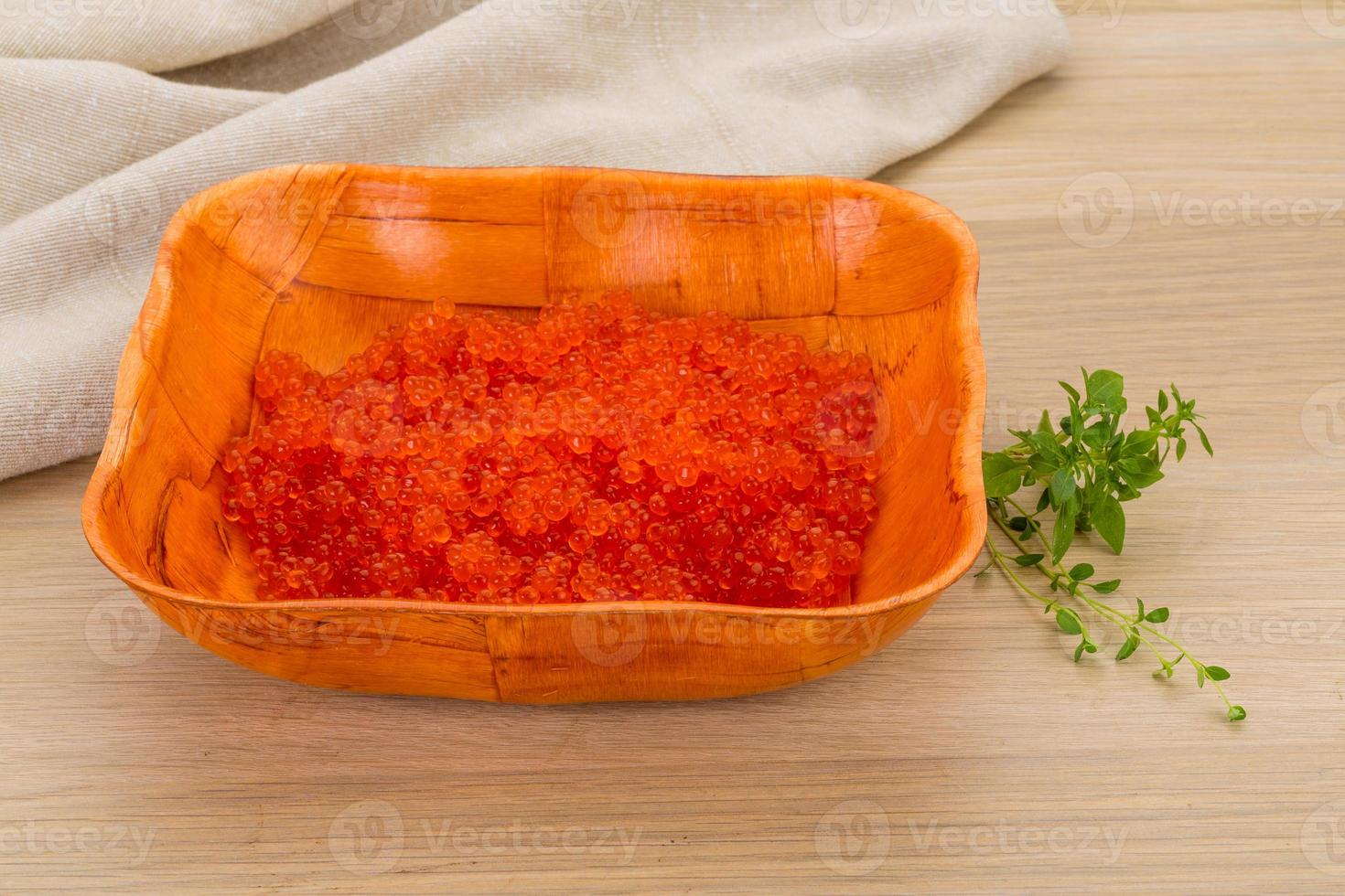 caviar rojo en un recipiente sobre fondo de madera foto