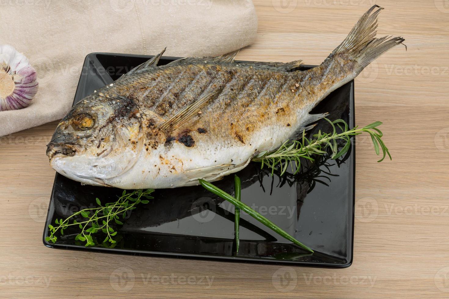 dorado a la parrilla en el plato y fondo de madera foto