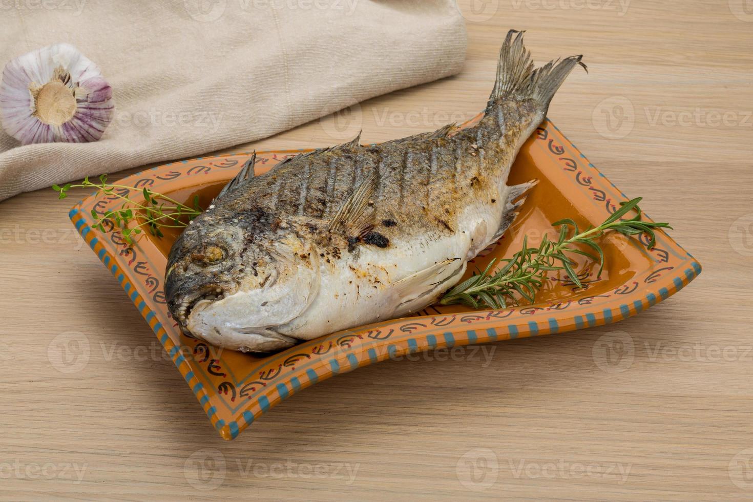 Grilled dorado on the plate and wooden background photo