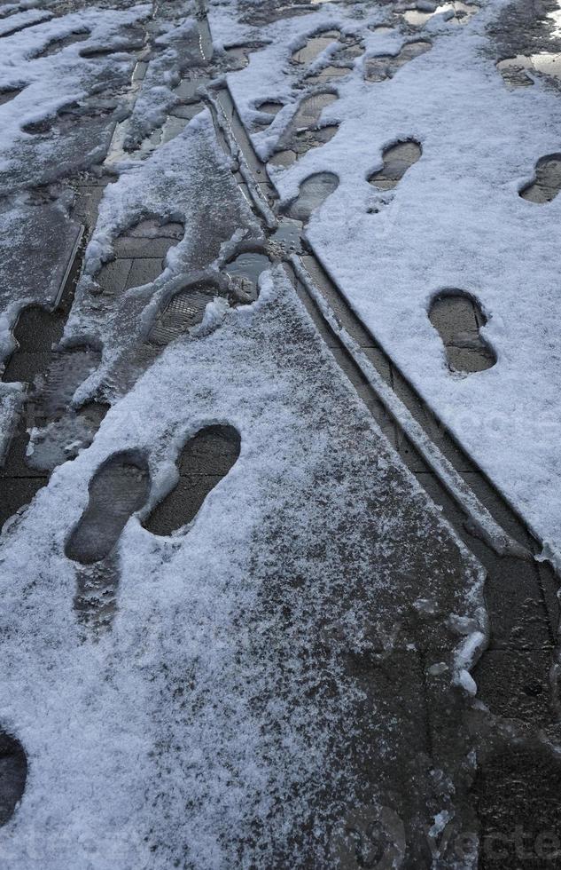 huellas en el derretimiento de la nieve en el suelo en una zona peatonal foto