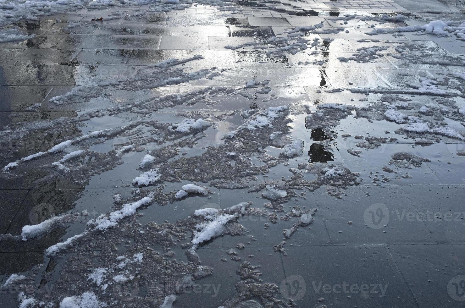 Foot prints in melting snow on the ground in a pedestrian zone photo