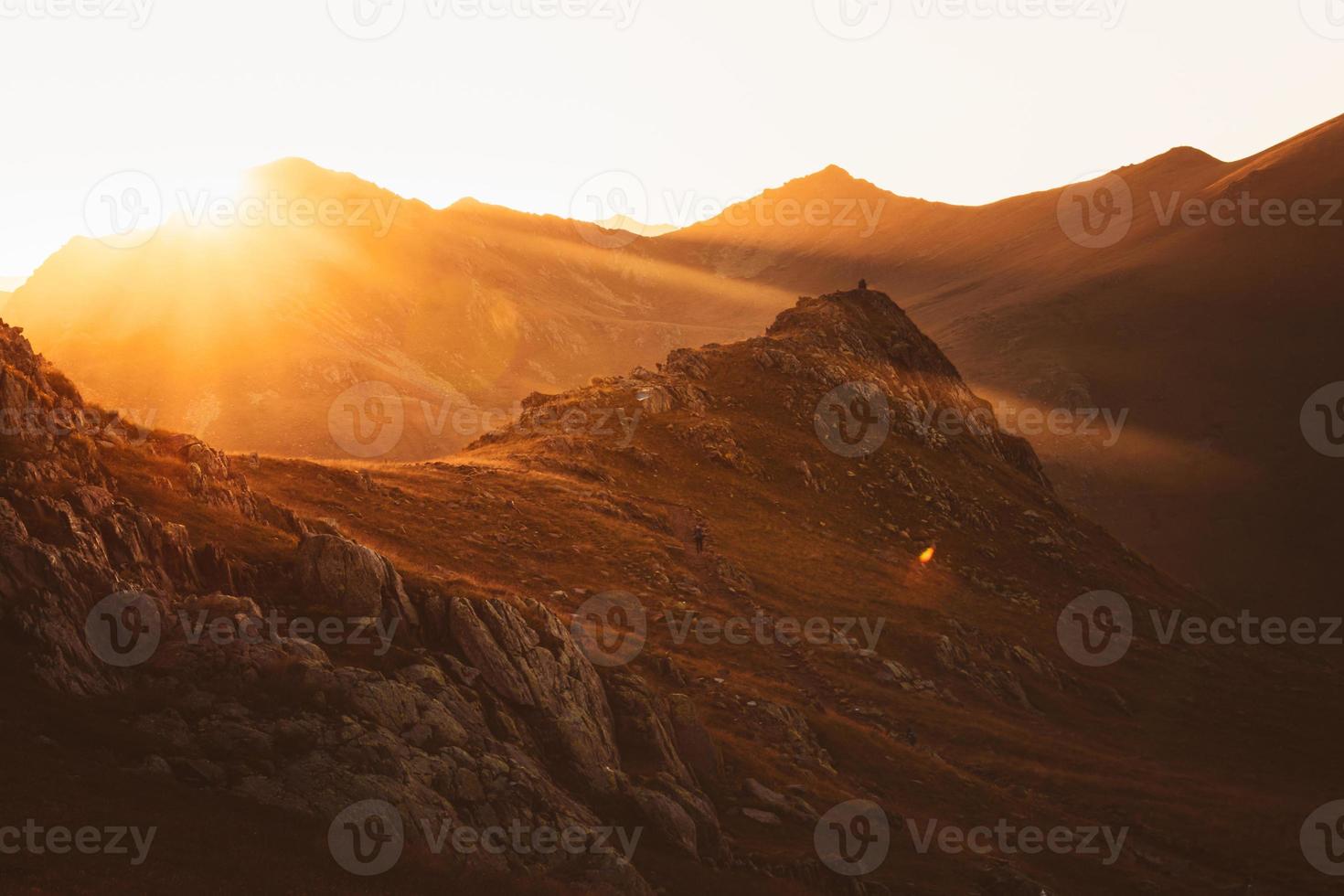 Couple of hikers in distance hike on trail up outdoors on beautiful sunset in autumn together. Active people on trek in caucasus mountains photo