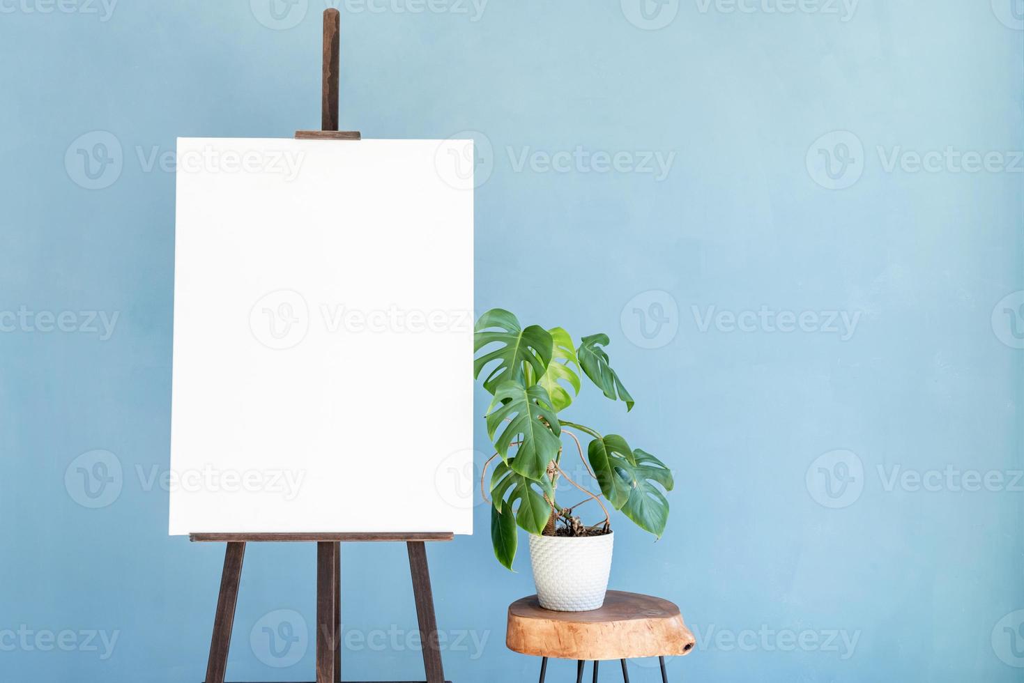 Wooden easel with blank canvas on light blue background for mockup design photo