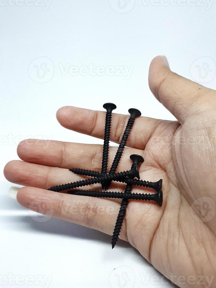 Isolated white photo of a hand carrying six black bolts