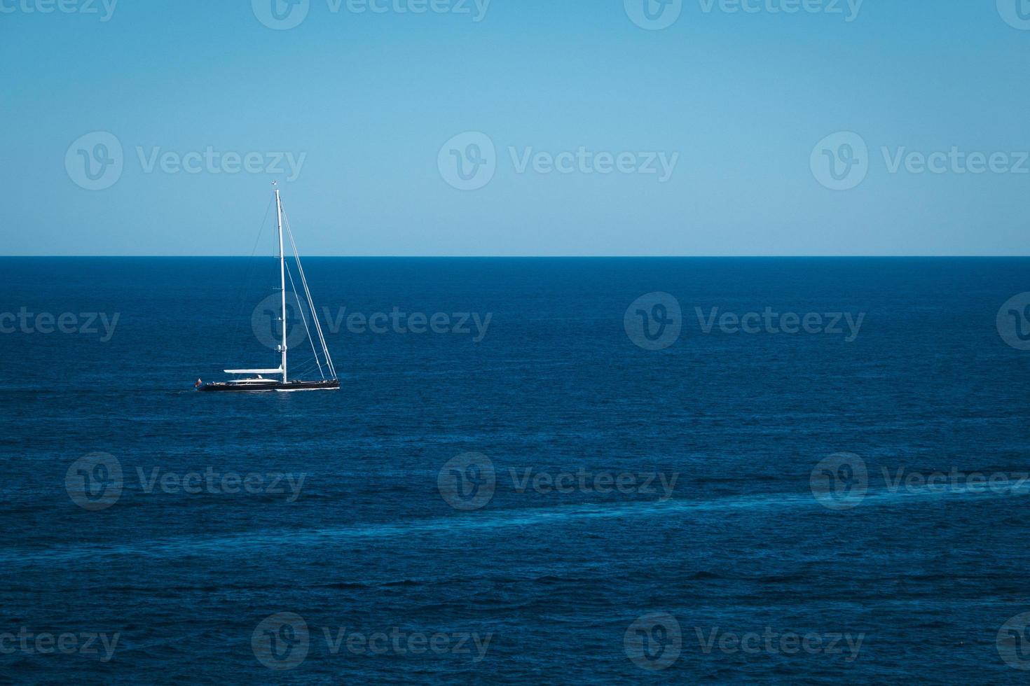 yate en el fondo del mar azul, pequeña aventura en velero, paisaje marino, viaje en barco a través del horizonte oceánico profundo. foto