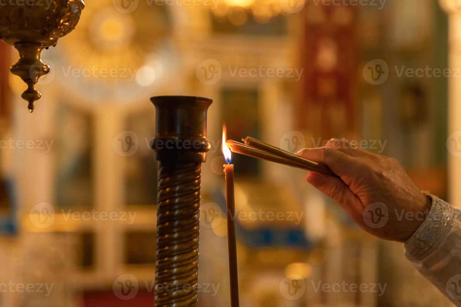 Orthodox Church. Christianity. Hand of priest lighting burning candles in traditional Orthodox Church on Easter Eve or Christmas. Religion faith pray symbol. photo