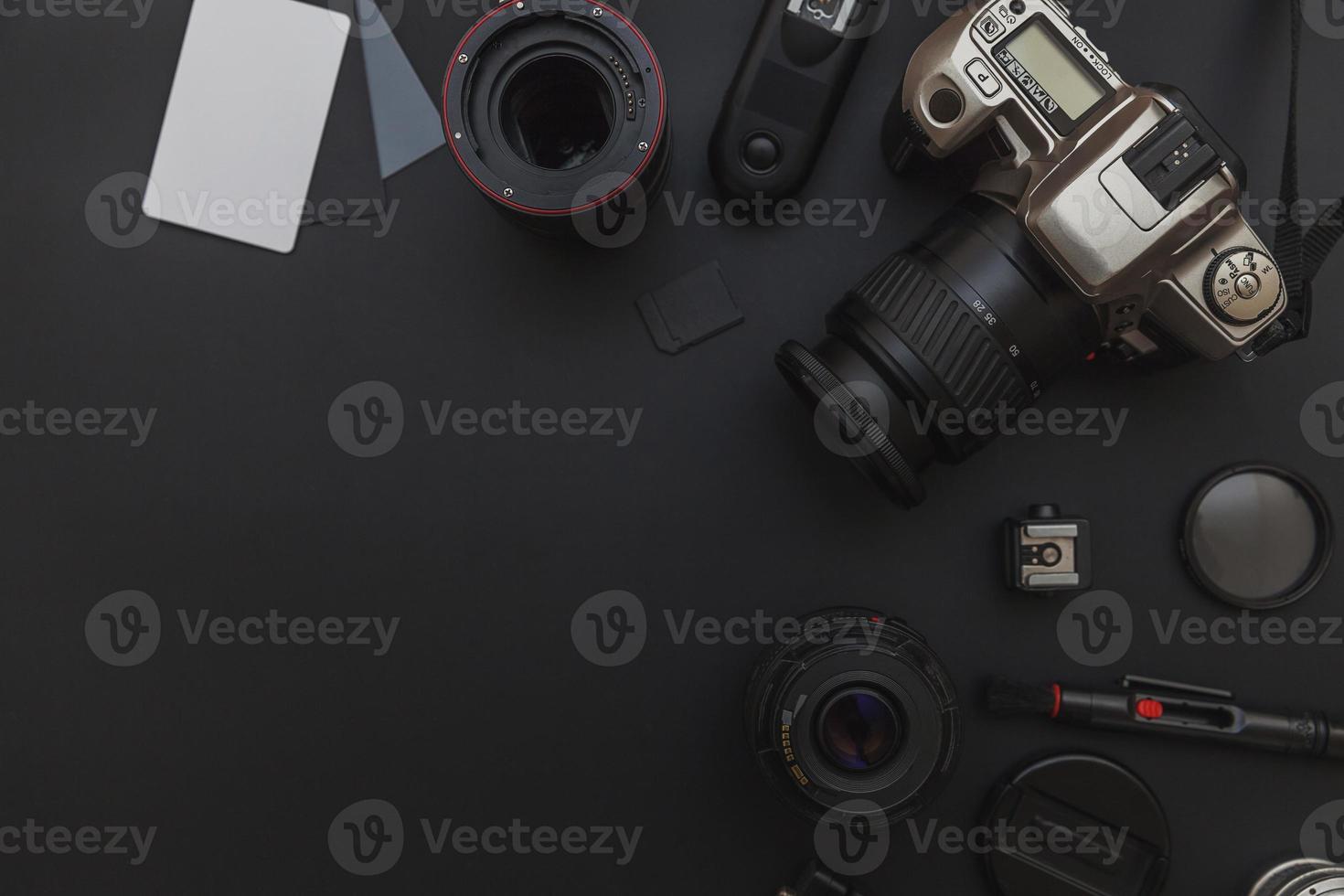 Photographer work place with dslr camera system, camera cleaning kit, lens and camera accessory on dark black table background. Hobby travel photography concept. Flat lay top view copy space. photo