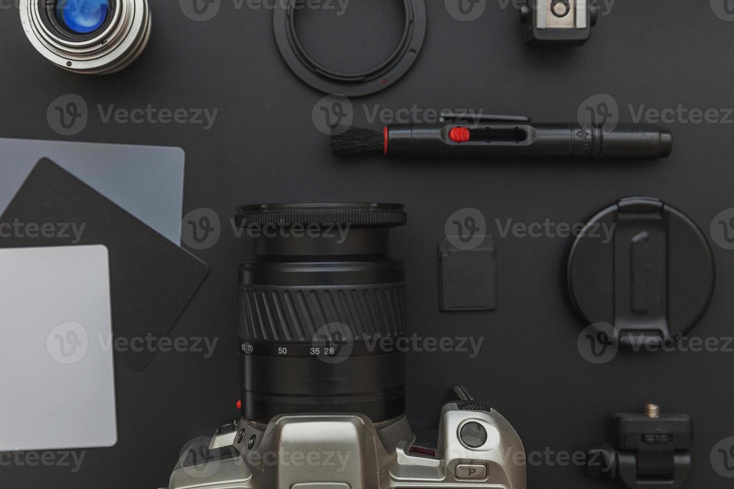 lugar de trabajo del fotógrafo con sistema de cámara dslr, kit de limpieza de cámara, lente y accesorio de cámara sobre fondo de mesa negro oscuro. concepto de fotografía de viajes de hobby. espacio de copia de vista superior plana. foto