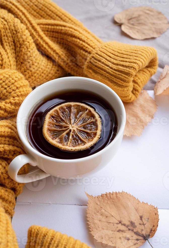 Cozy autumn composition, sweater weather. Pumpkins, hot tea and sweaters on window photo