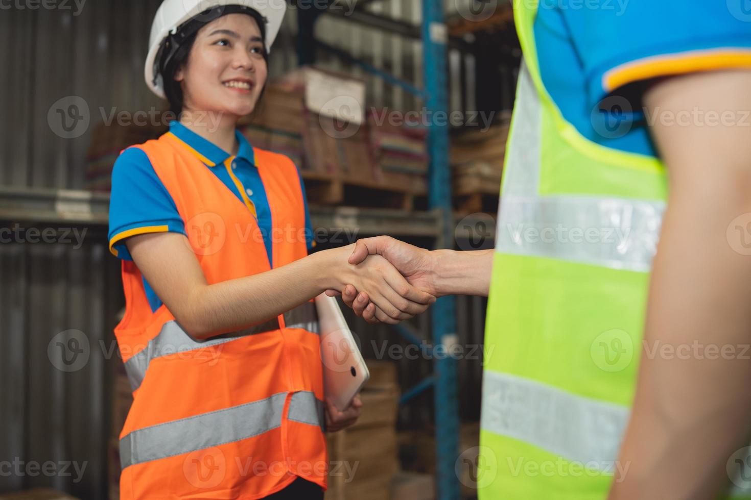 Industrial warehouse asian worker in safety suite handshake celebrate successful or deal commitment. Logistics , supply chain and warehouse business.Teamwork unity under view concept. photo