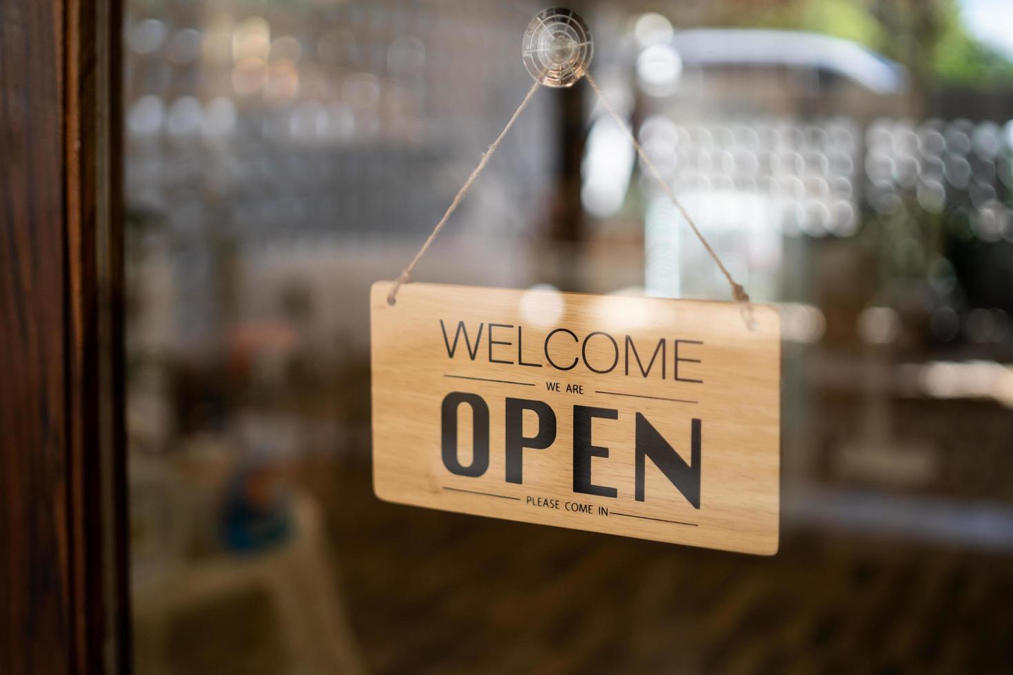 señal abierta amplia a través del fondo del bokeh de cristal de la puerta. Abra el letrero a través del cristal de la ventana de la tienda. puerta de tablero de madera de texto letrero de tienda vintage tienda abierta. foto