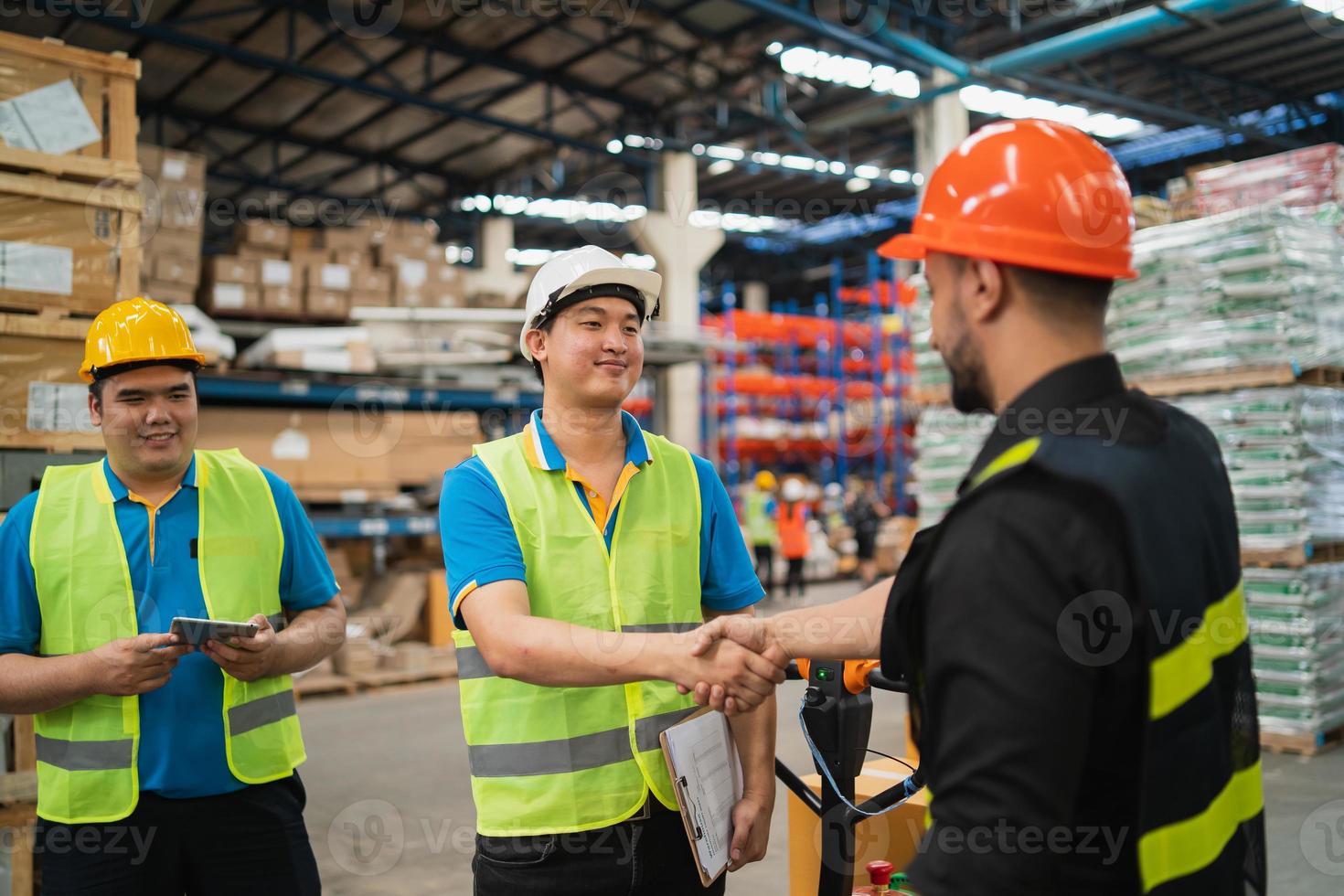 Industrial warehouse worker or engineer in safety suite handshake celebrate successful or deal commitment. Logistics , supply chain and warehouse business.Teamwork unity under view concept. photo