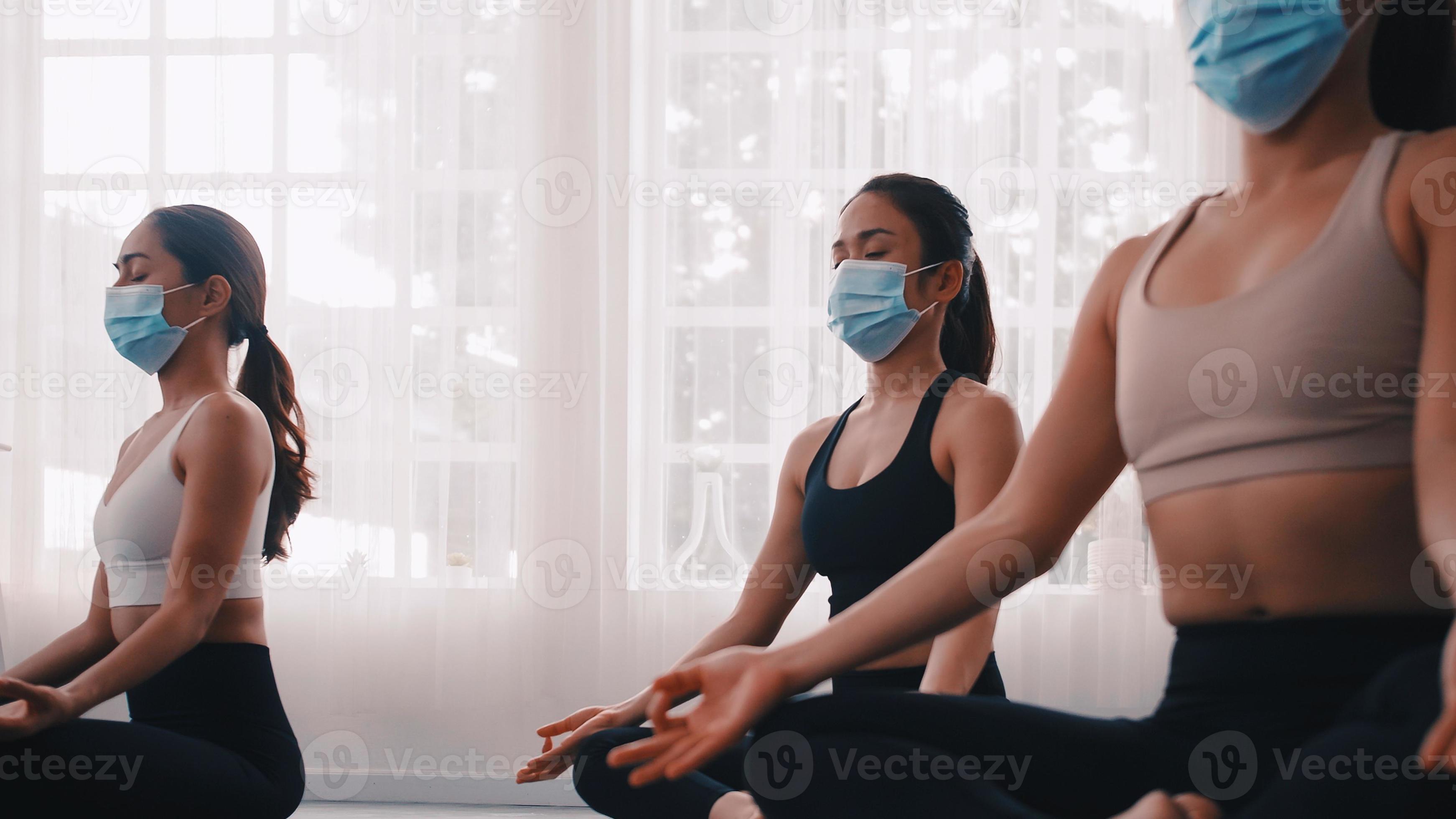 A group of Asian women wearing medical masks while doing yoga exercise