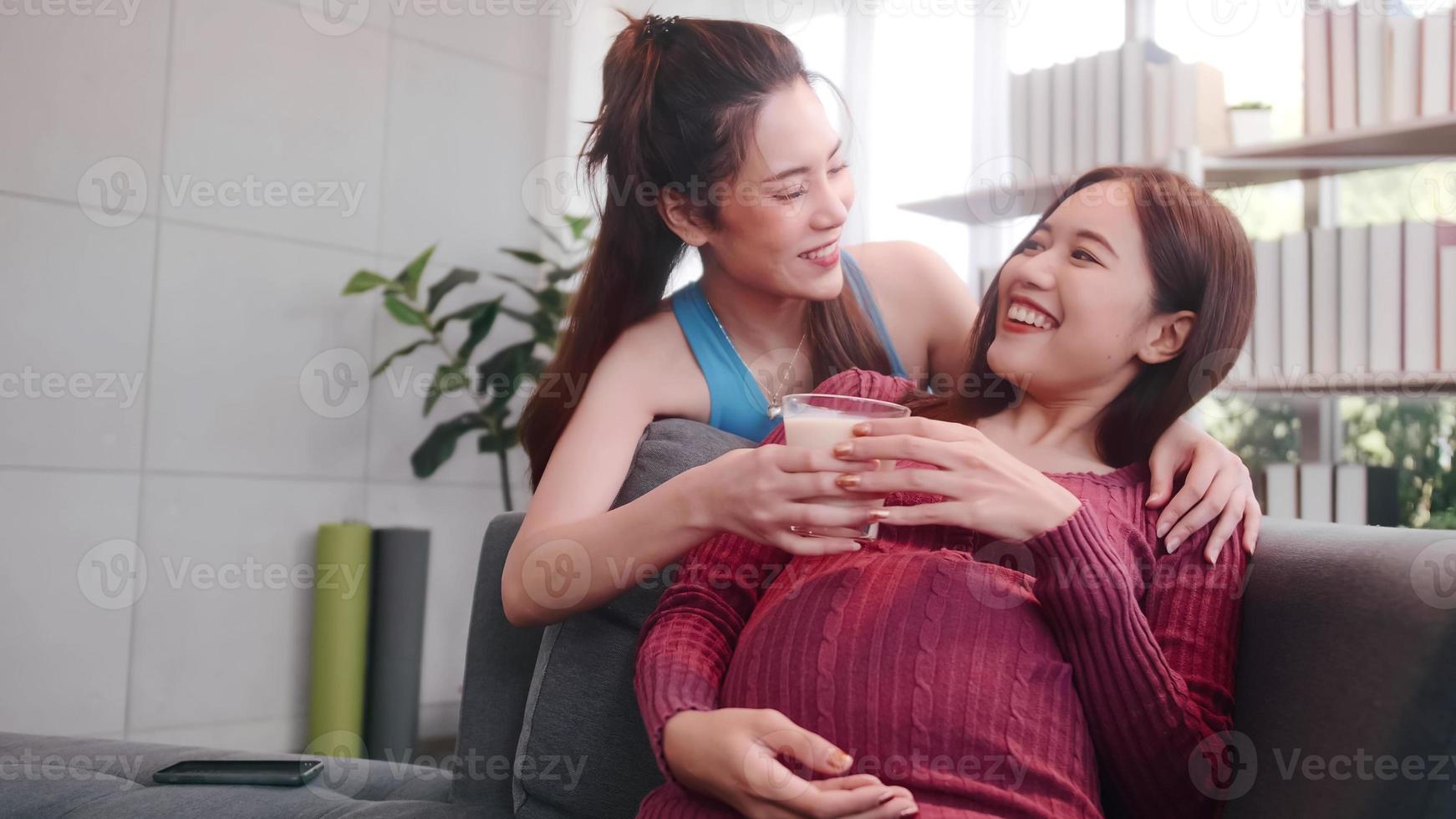 Happy pregnant lesbian couple spending time together at home. photo
