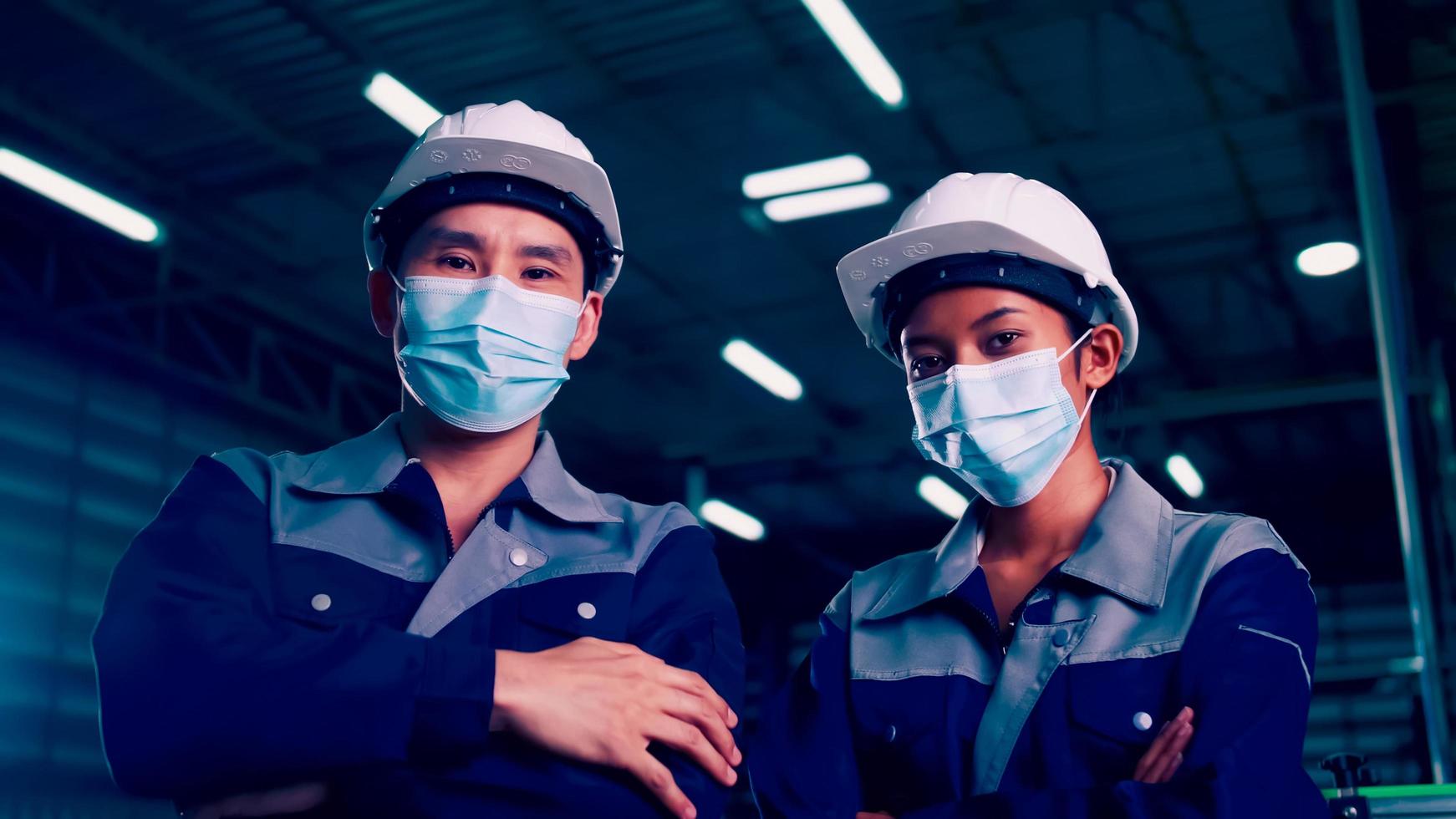 Asian team of engineers wearing medical face masks working together in factory under COVID-19 situation photo
