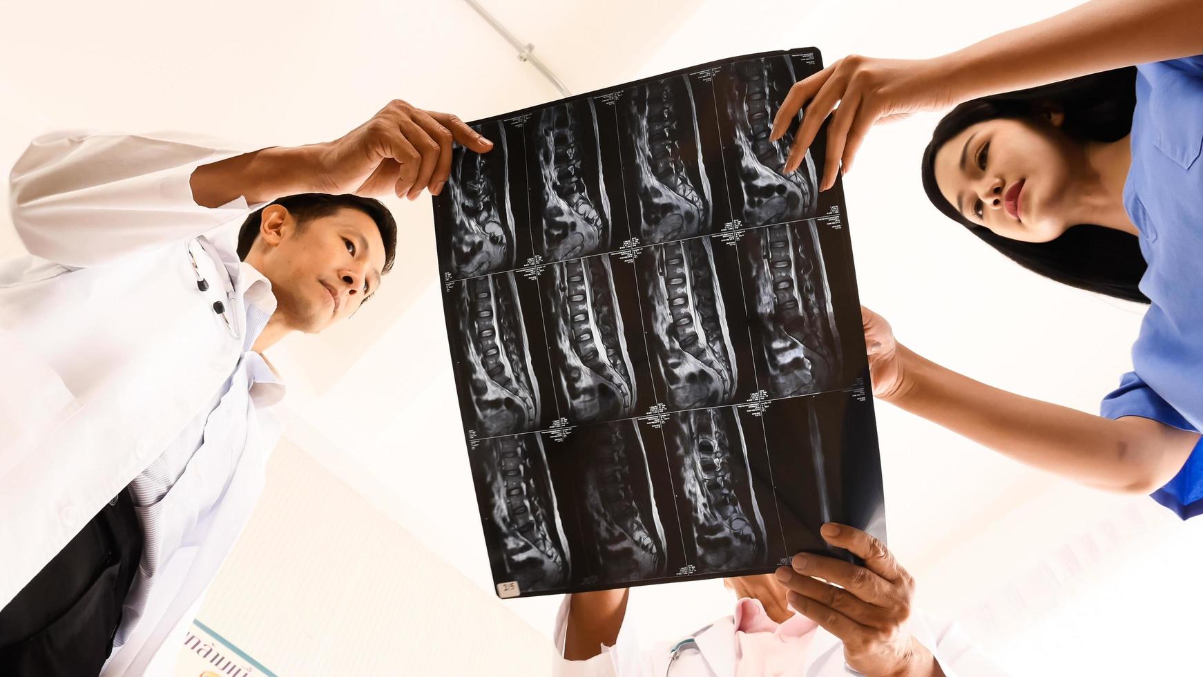 Doctor and medical assistants discussing about diagnosis result on x-ray film. photo