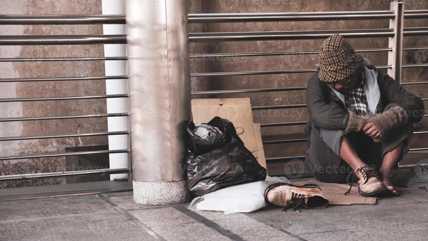 Homeless man sitting on outdoor floor. photo