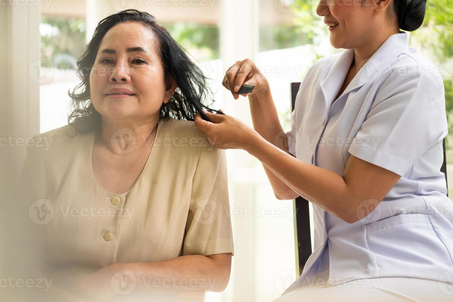 Nurse combing adult femal patient hairs in the room. photo