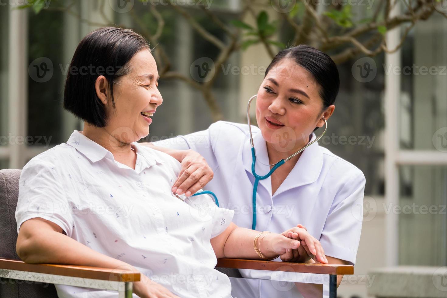 Asian nurse auscultating for female patient by using stethoscope at the hospital park photo