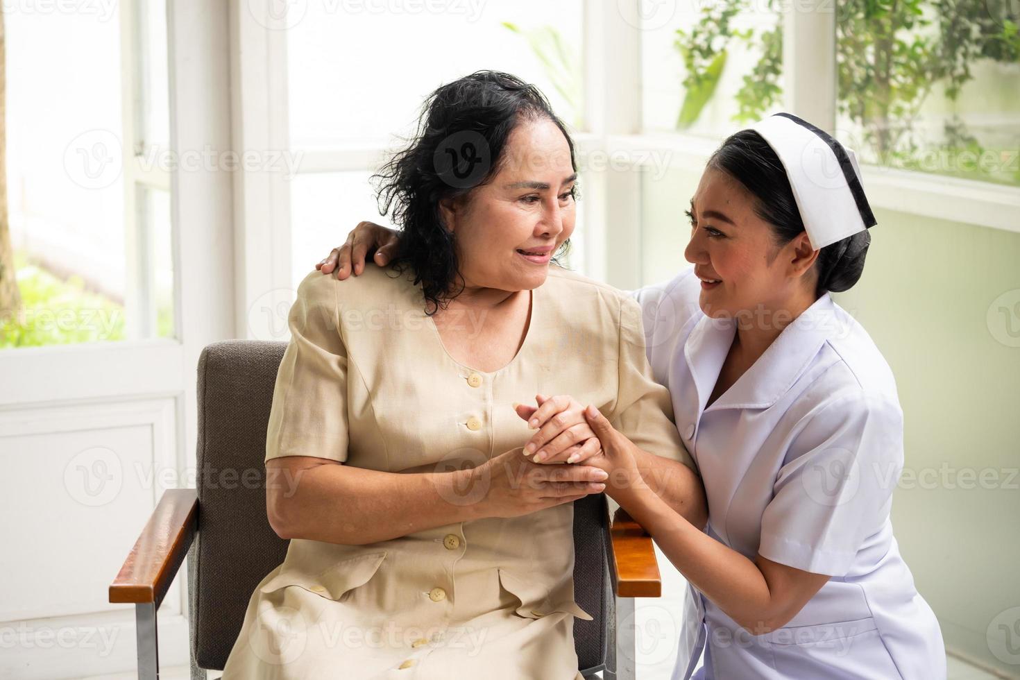 Beautiful nurse comforting female patient in the room. photo